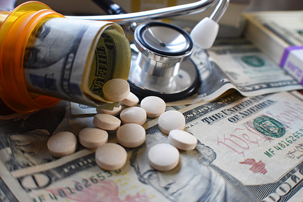 money with pills spilling out of bottle and stethoscope