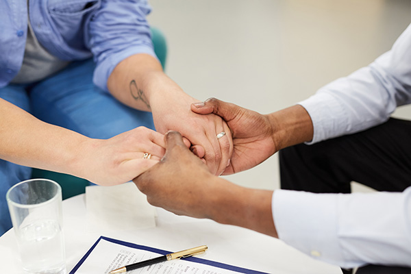 two people holding hands in a therapy/substance use treatment setting
