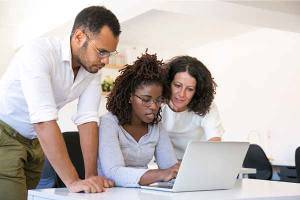 three people looking at a laptop