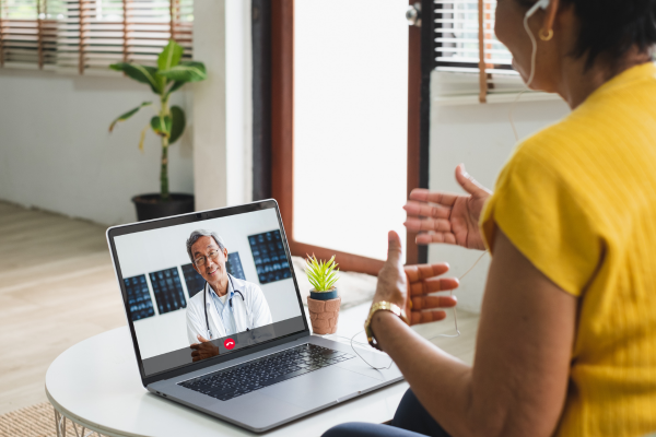 Woman wearing head phones talking to virtual doctor on a laptop