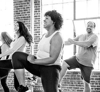 Black and white image of group of people in a fitness class working out